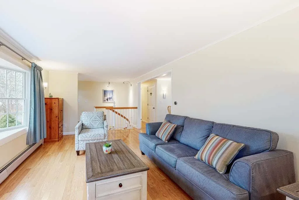 A bright living room with a blue sofa and a wooden coffee table.