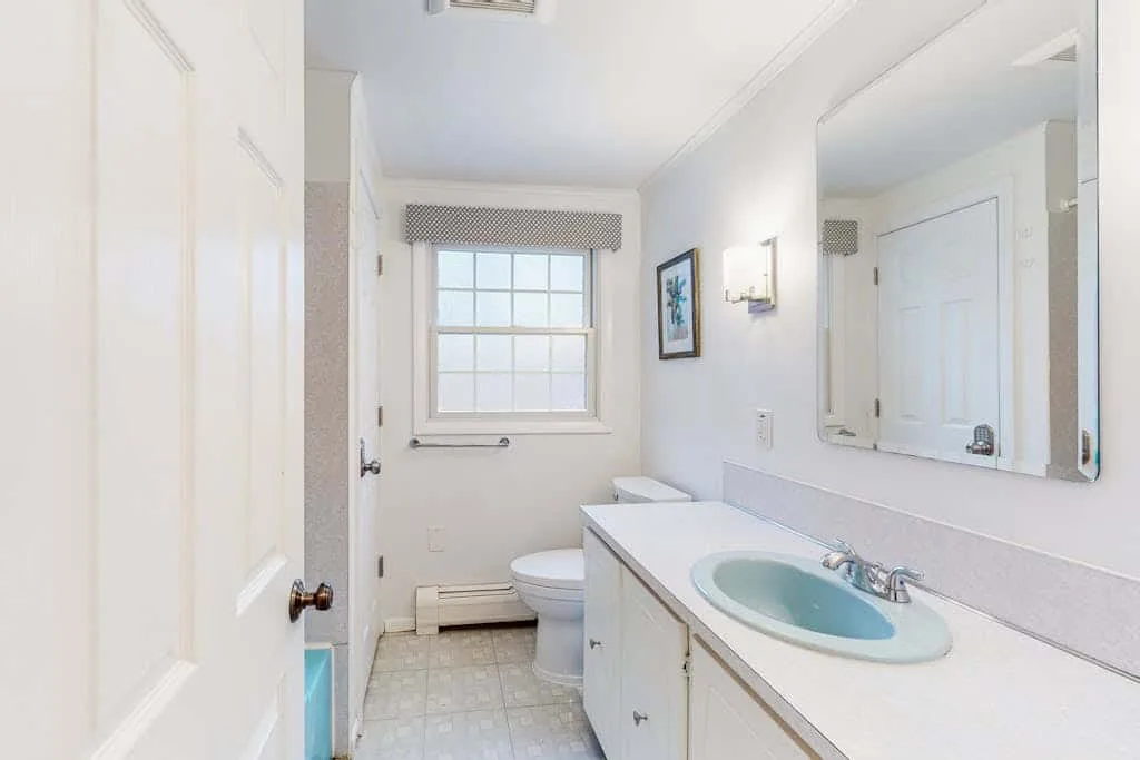 Un baño luminoso con tocador, lavabo y ventana.