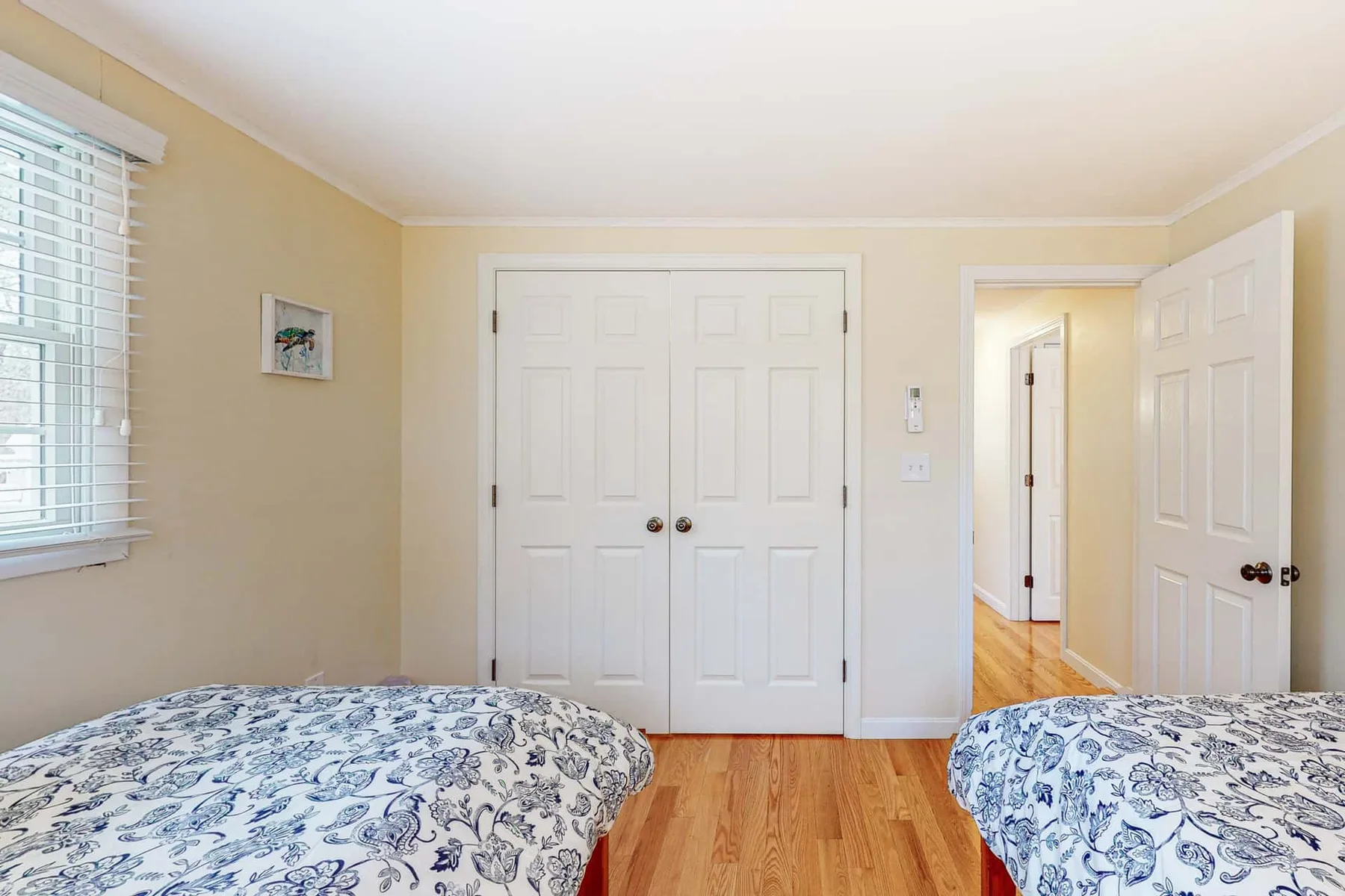 Un dormitorio con ropa de cama estampada, una ventana y una puerta abierta.