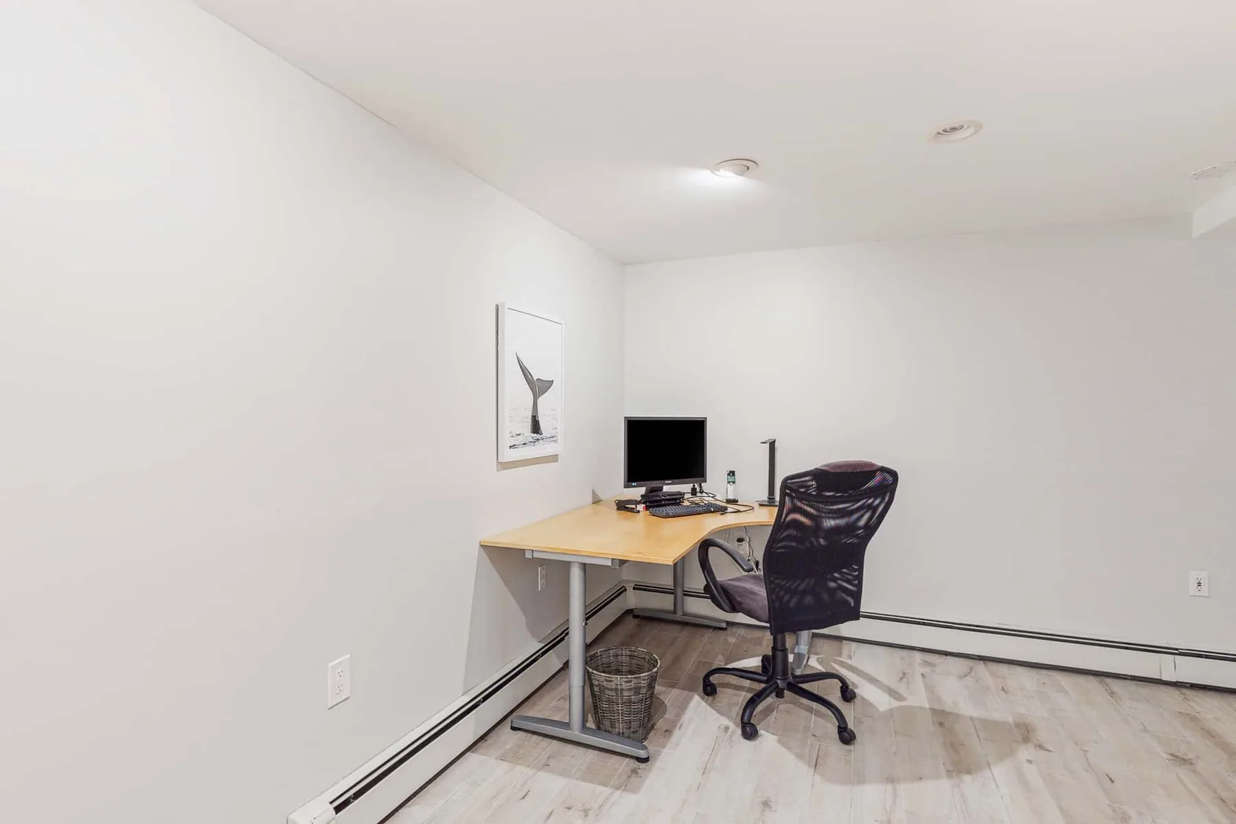 Una pequeña oficina con escritorio, computadora y silla con ruedas.