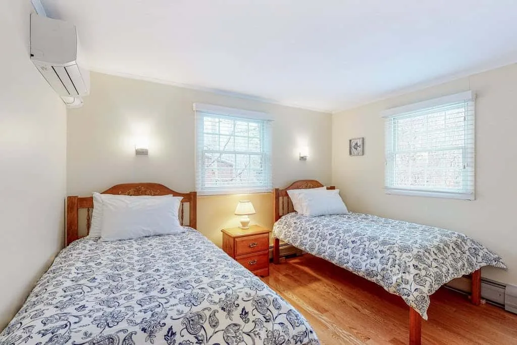 Un dormitorio luminoso con dos camas, ropa de cama estampada y ventanas.