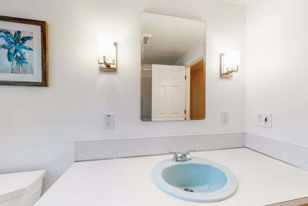 Un tocador de baño con un lavabo azul claro y un espejo encima.