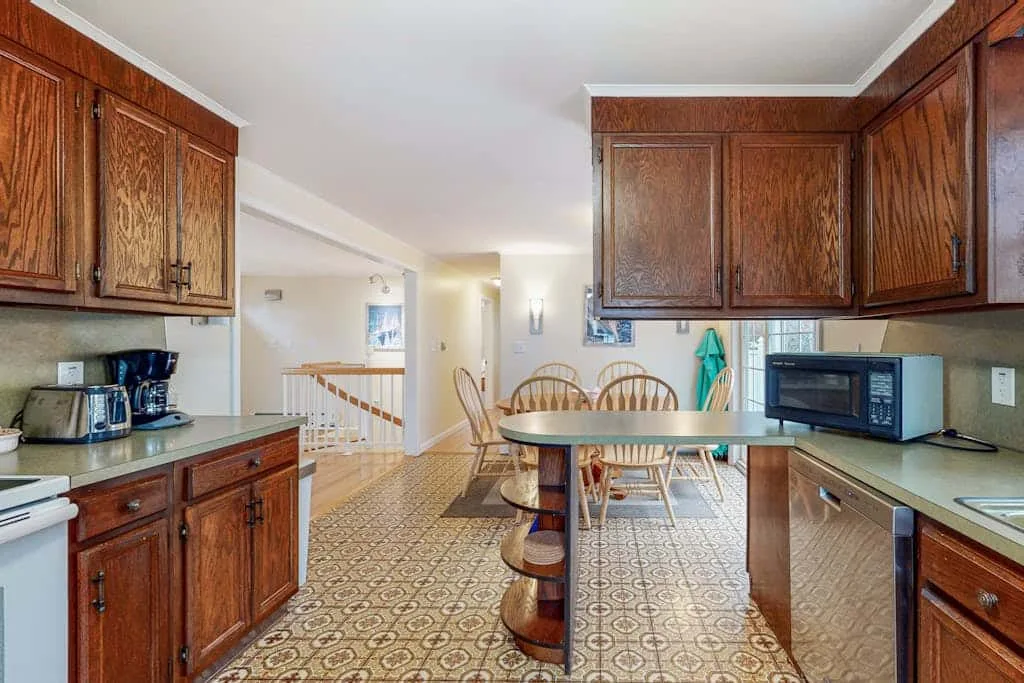 Una cocina con gabinetes de madera, una barra central y una mesa de comedor.