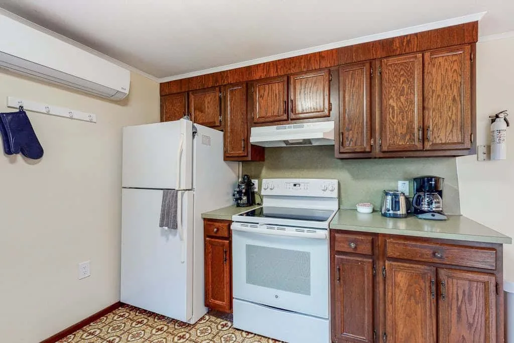 Una cocina compacta con gabinetes de madera, un refrigerador y una estufa blanca.