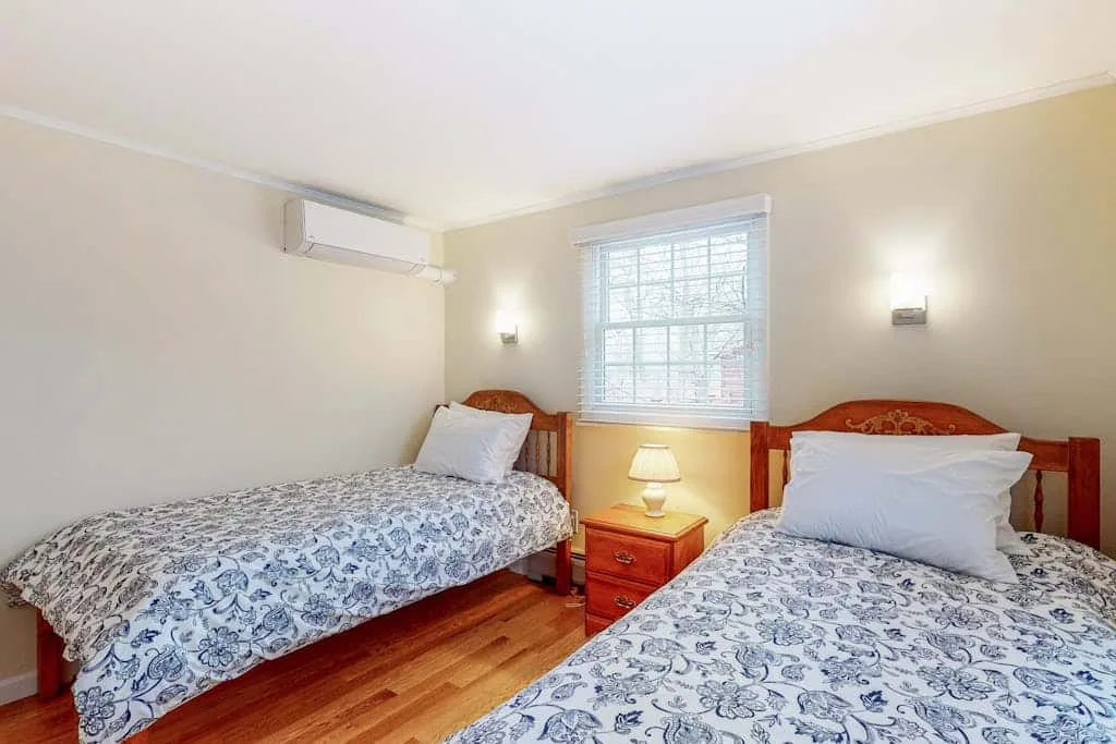 Un dormitorio luminoso con dos camas y una ventana entre ellas.