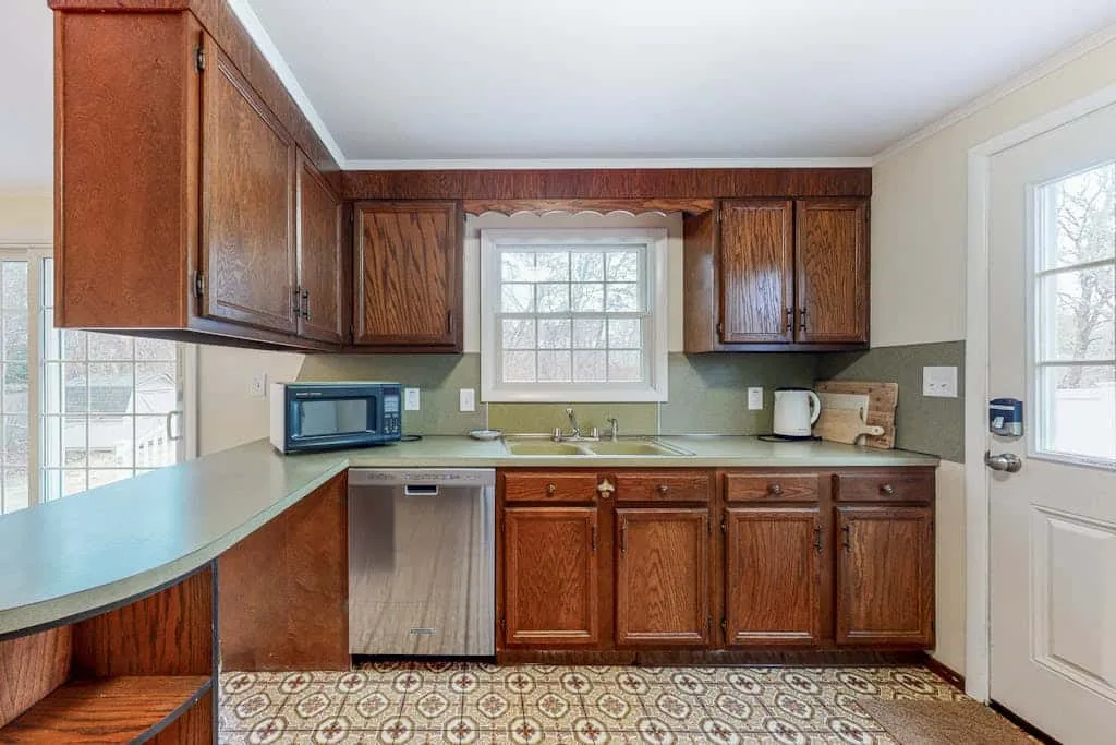 Una cocina con gabinetes de madera, encimeras y una ventana sobre el fregadero.