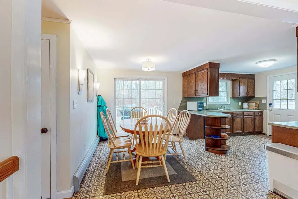 A dining area opens into a kitchen, with a wooden table and chairs.