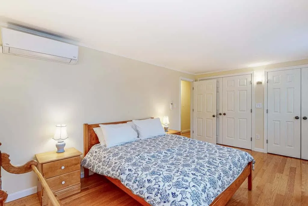 Un dormitorio con una cama, mesillas de noche y varias puertas cerradas.