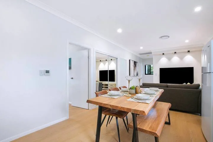 An open-plan dining and living area with a wooden dining table and seating.