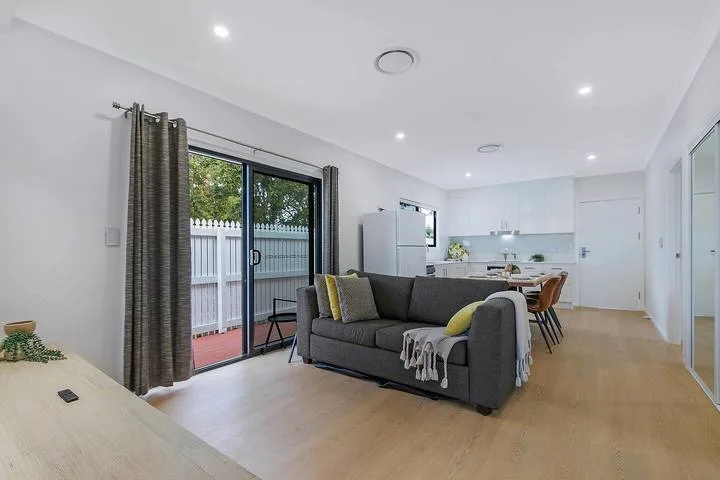 Una sala-comedor diáfana con una zona de asientos gris y cocina.