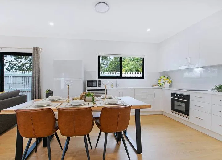 Una luminosa cocina-comedor diáfana con una mesa de comedor de madera.