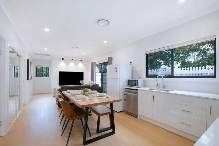 A bright open-plan dining and kitchen area with a table and counter.
