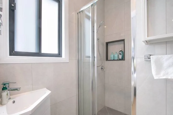 Bathroom with a shower, sink, and window.