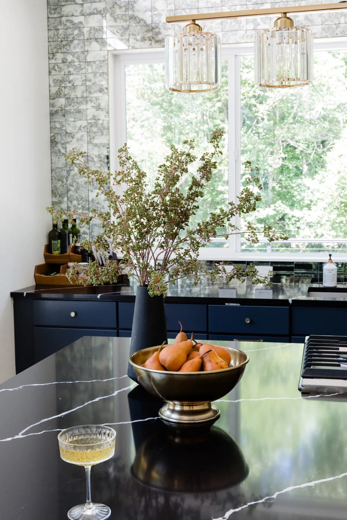 Una cocina luminosa con una isla oscura y un cuenco de peras.