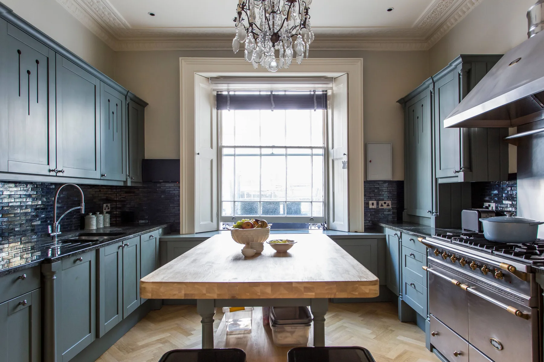 A bright kitchen with blue cabinetry and a central island beneath a large window.