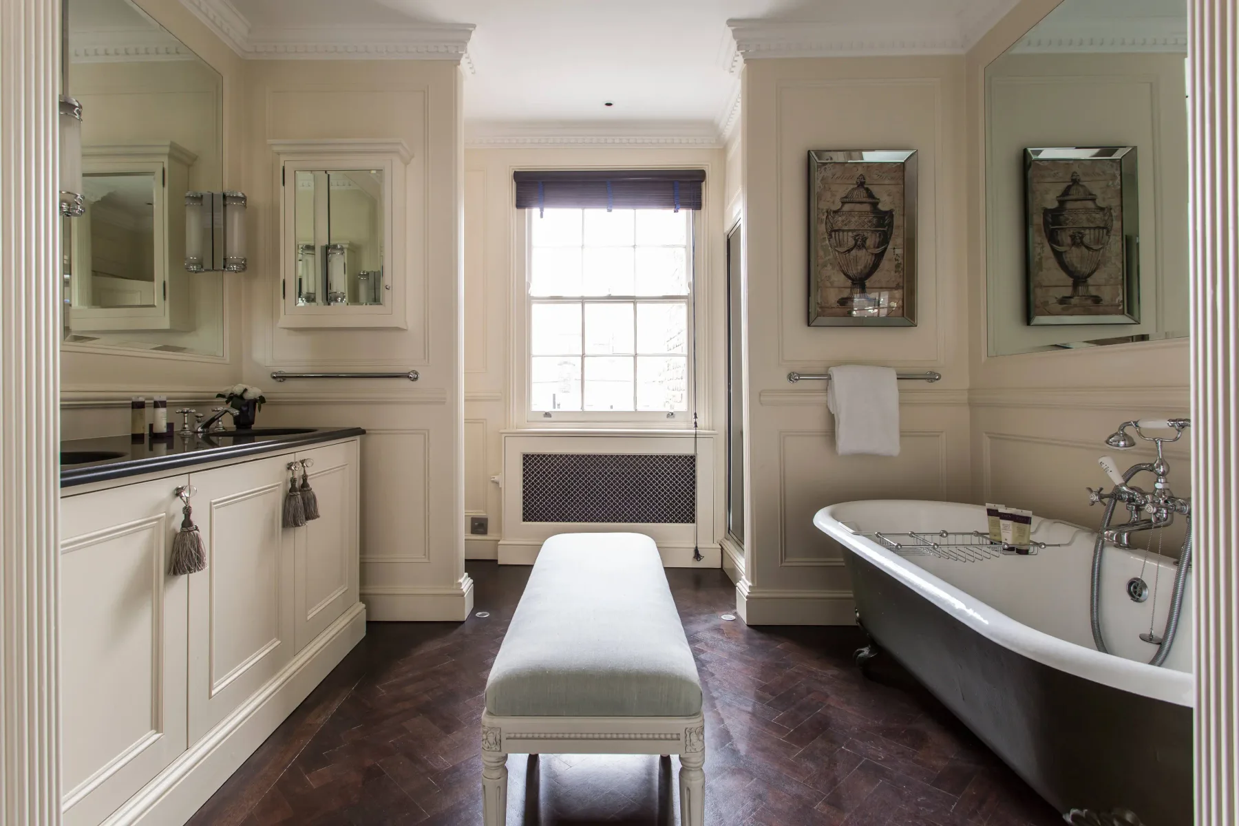 A bright bathroom with a freestanding bathtub and a padded bench.