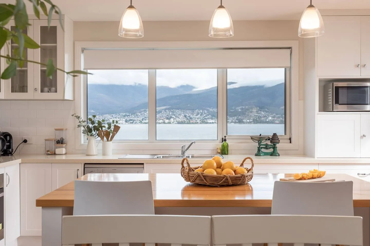 Una cocina y comedor luminosos con una amplia ventana que da a un lago y montañas.