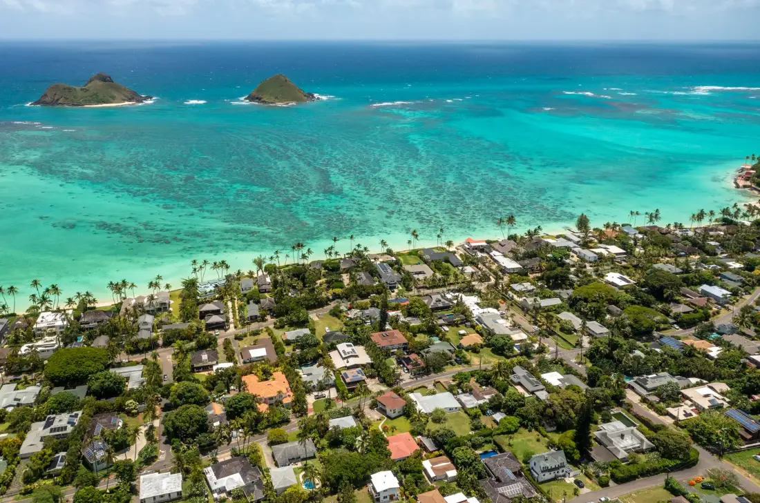 An aerial view of a coastal neighborhood beside turquoise water and offshore islets.