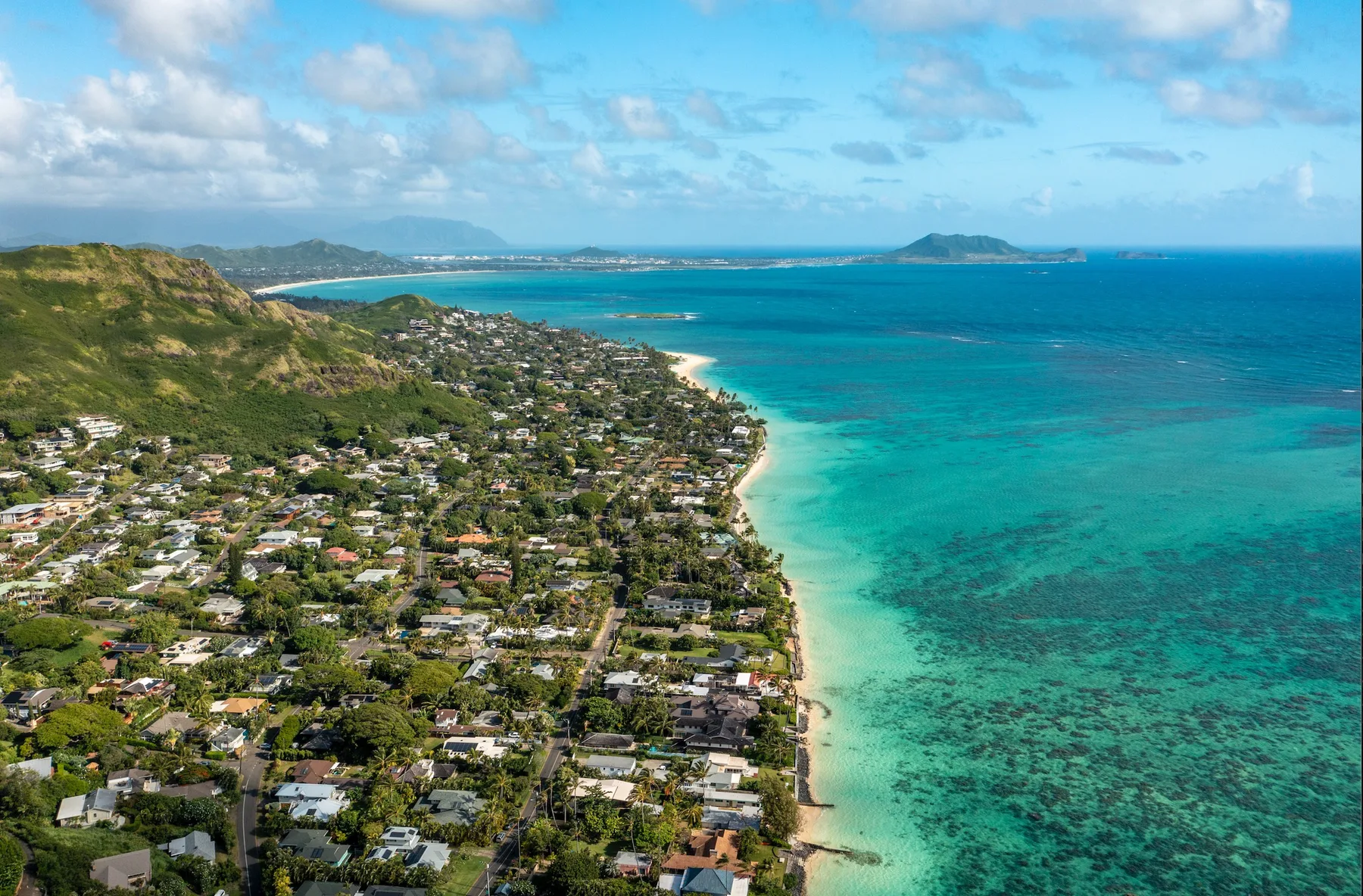 An aerial view of a coastal neighborhood beside a turquoise sea.