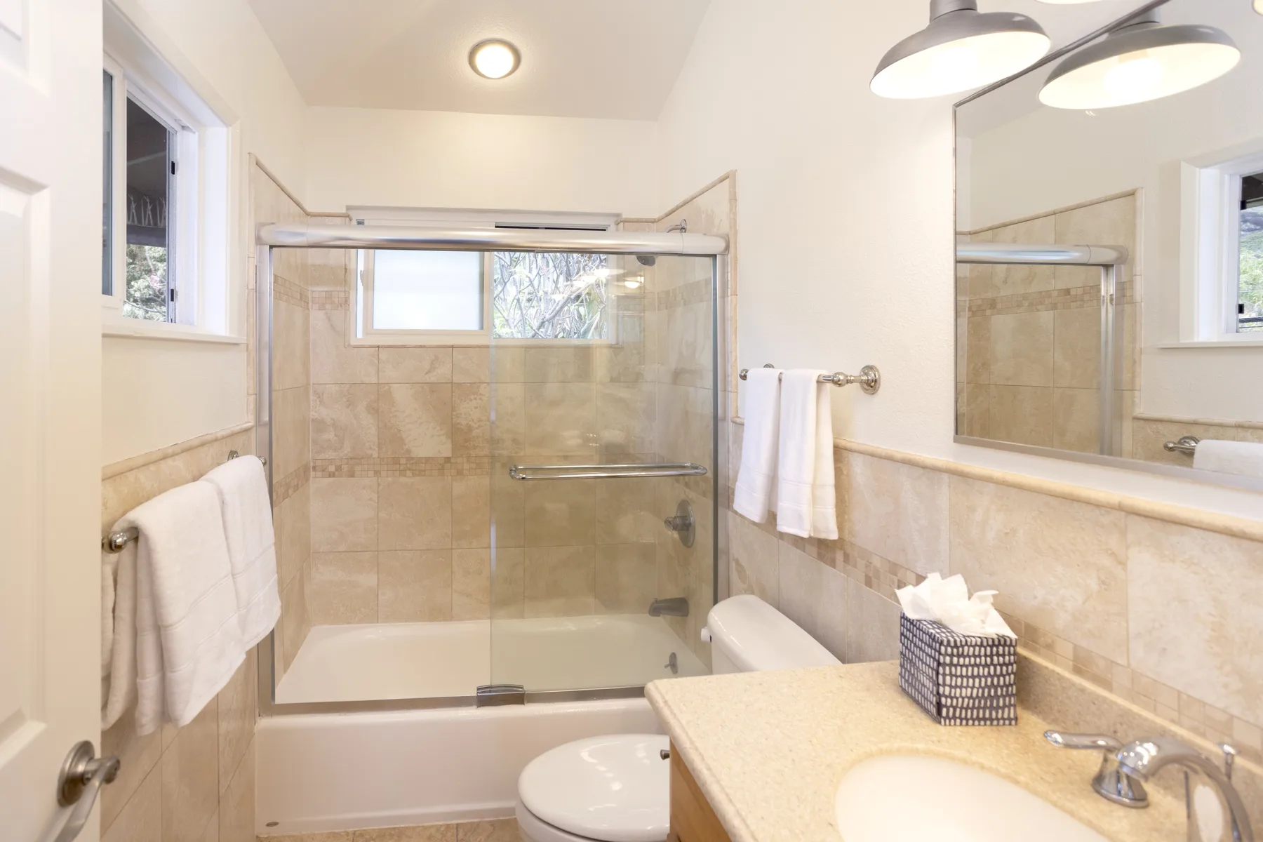 A bathroom with a glass shower enclosure, sink, and mirrored wall.