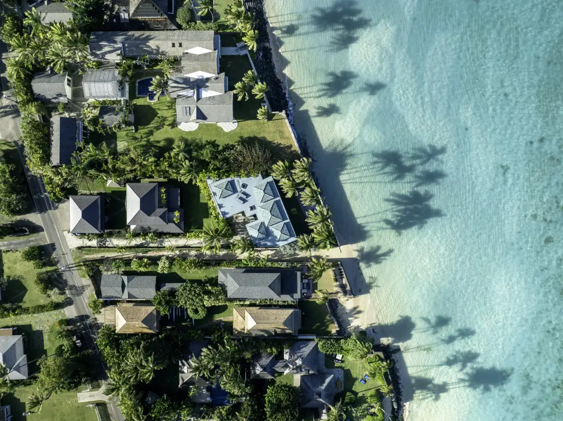An aerial view of a coastal resort beside a sandy beach and clear water.