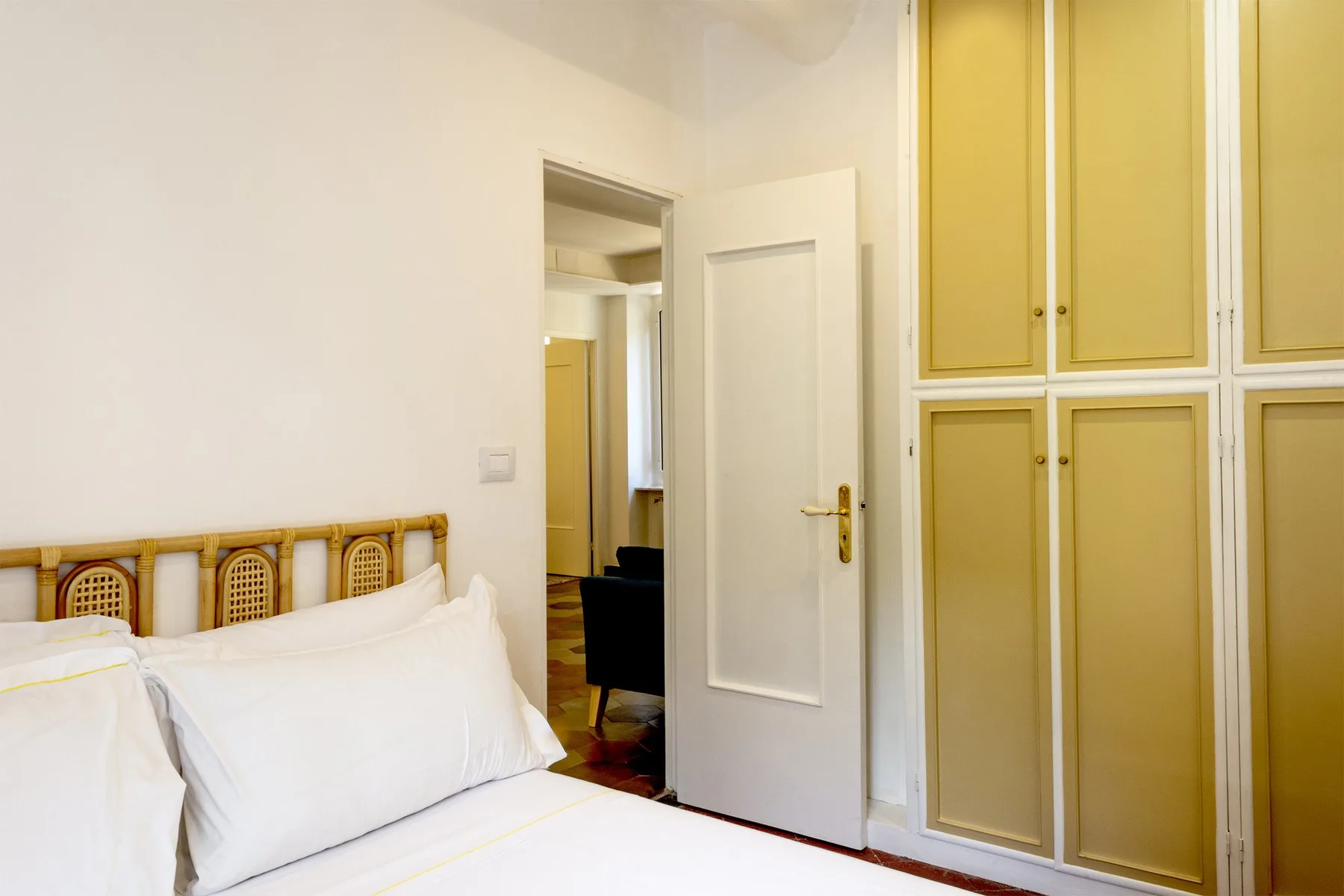 Un dormitorio con una cama junto a armarios empotrados y una puerta abierta.