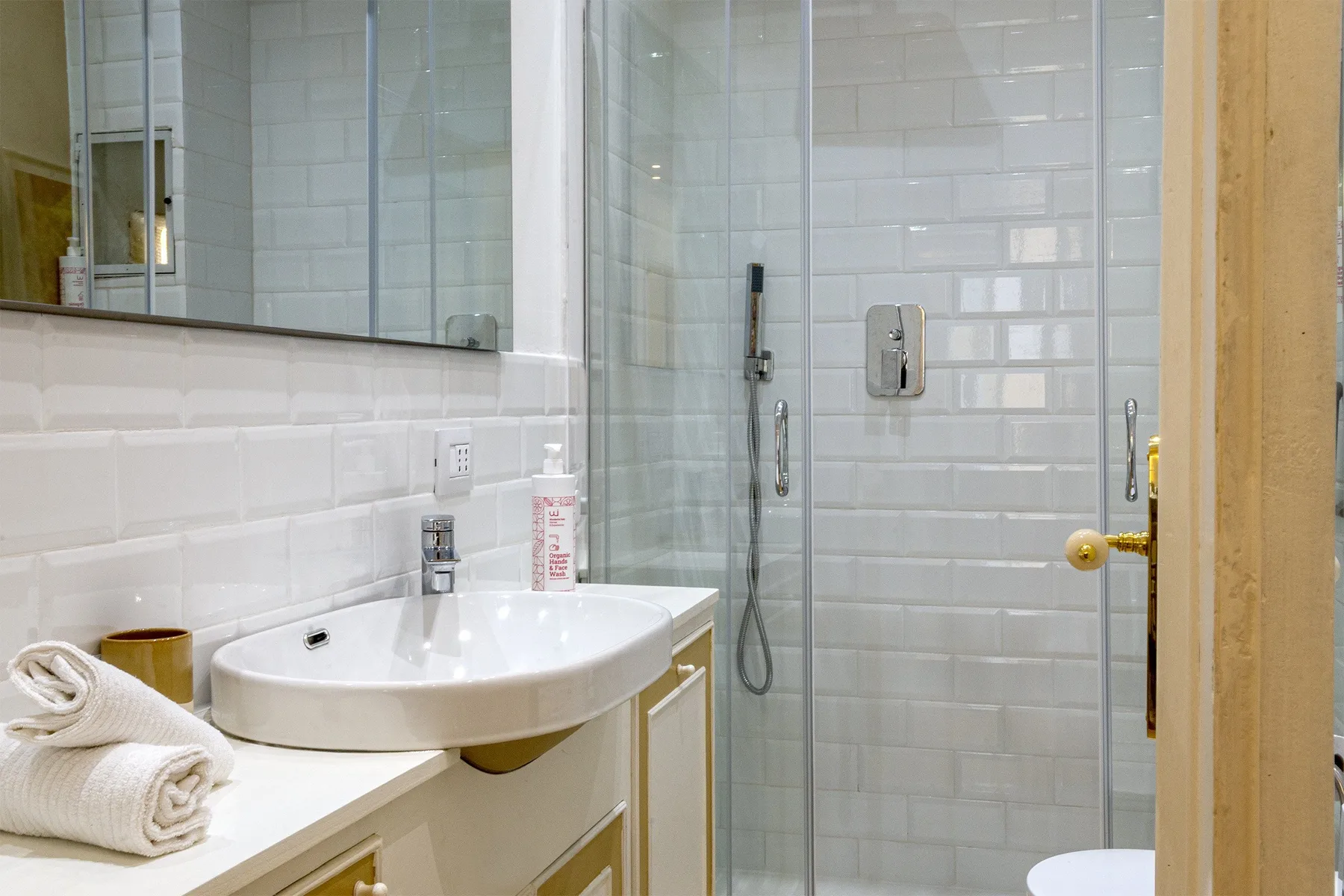 Baño alicatado con un lavabo junto a una ducha de cristal.