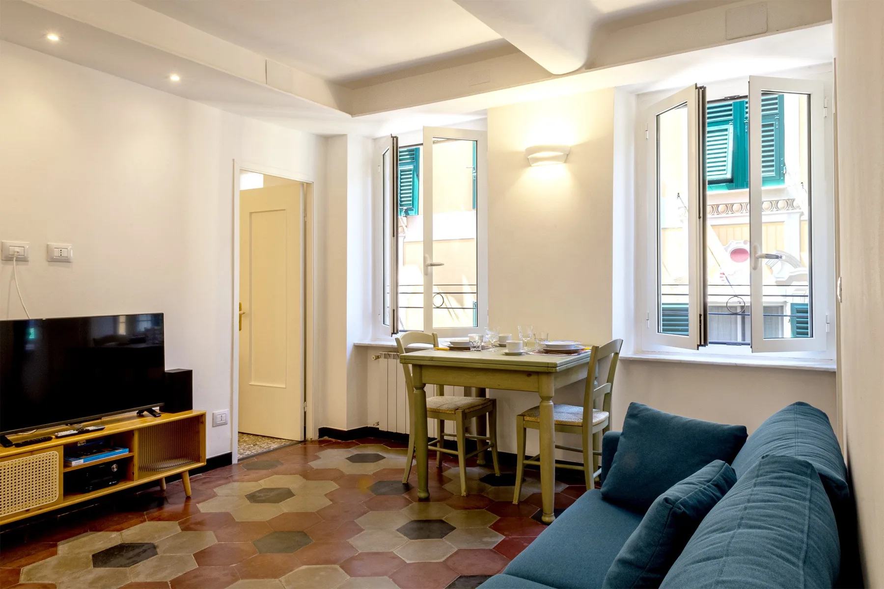 Una luminosa sala de estar y comedor con una mesa, asientos y grandes ventanas.