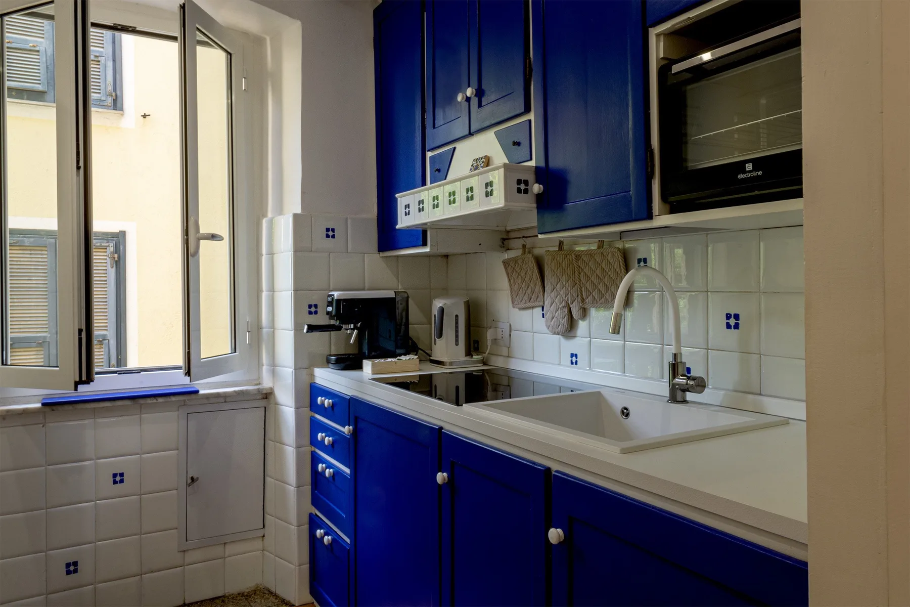 Una cocina luminosa con armarios azules, un fregadero y ventanas.