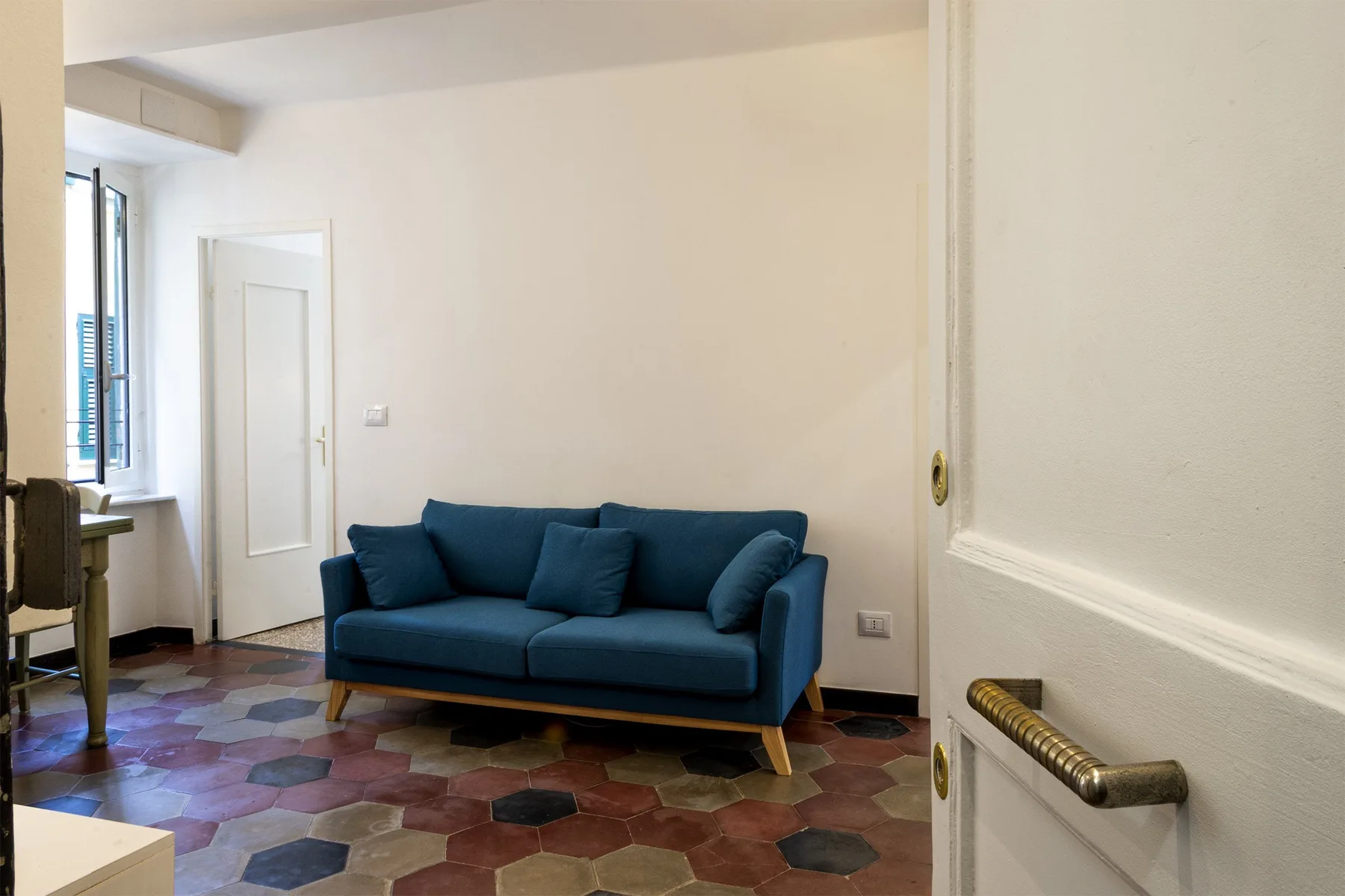 Una sala de estar con asientos azules y un suelo de baldosas de colores.