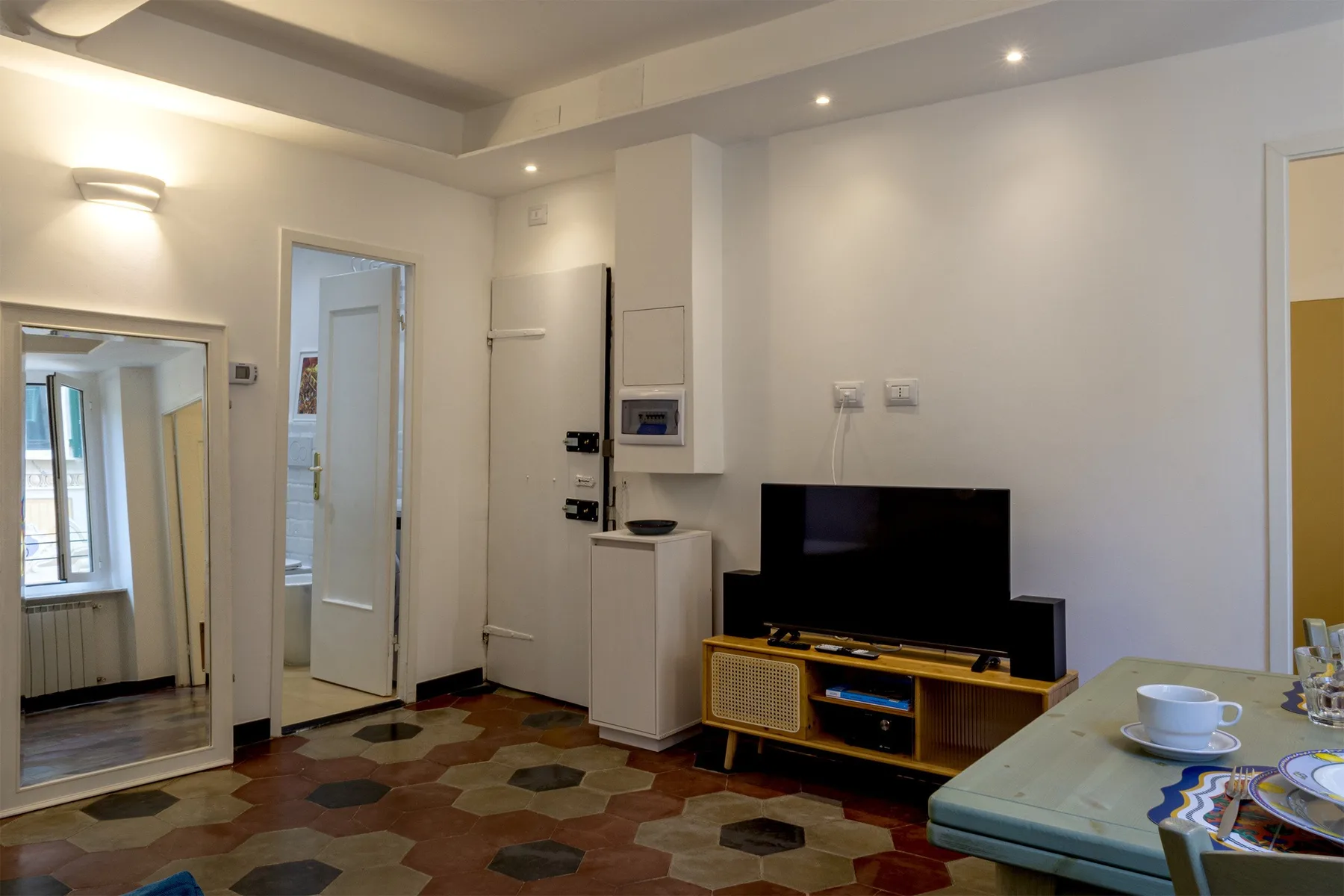 Una sala de estar con un televisor sobre un mueble de madera y una mesa de comedor.
