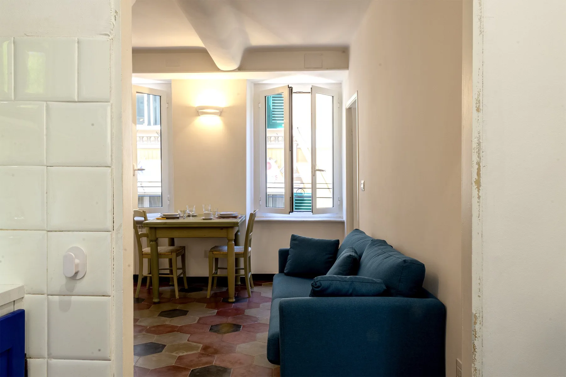 Una sala de estar con asientos azules y una mesa de comedor junto a las ventanas.