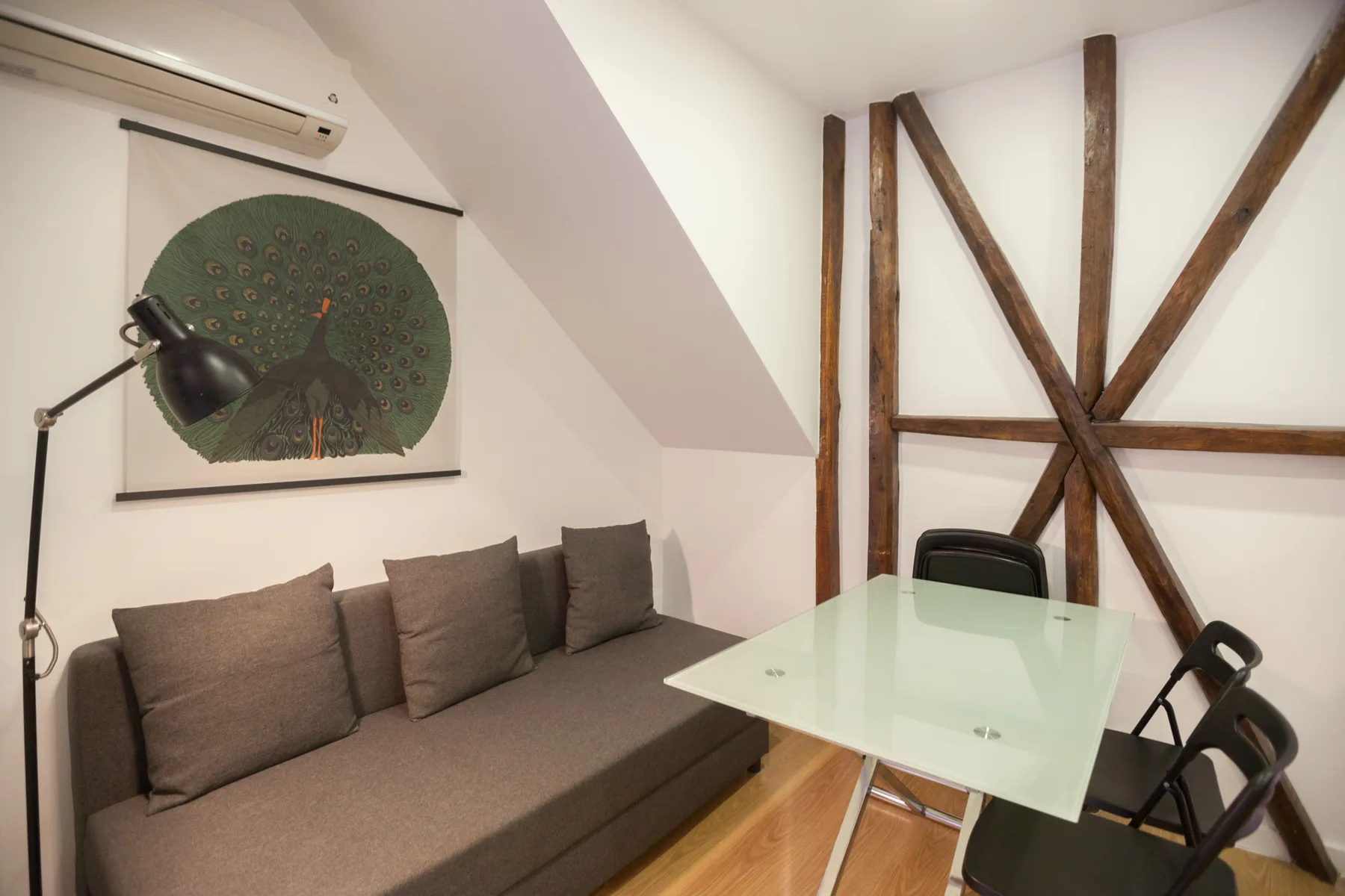 Una pequeña zona de estar y comedor con un sofá y una mesa de cristal.
