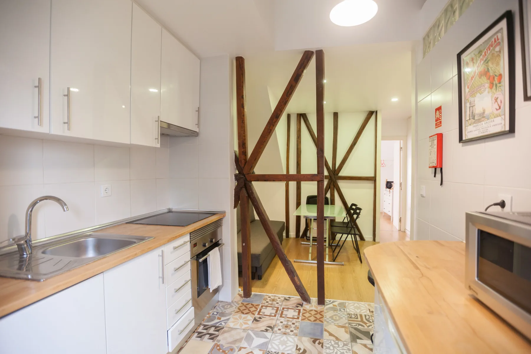 Una cocina luminosa con zona de comedor, encimera, mesa y vigas de madera a la vista.