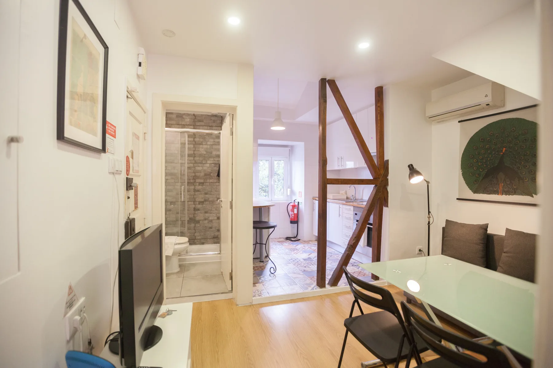 Interior luminoso de un apartamento con mesa de comedor y asientos junto a un baño.