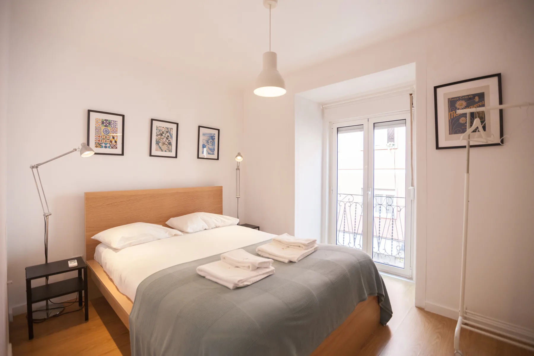 Un dormitorio luminoso con una cama y puertas de vidrio que dan a un pequeño balcón.