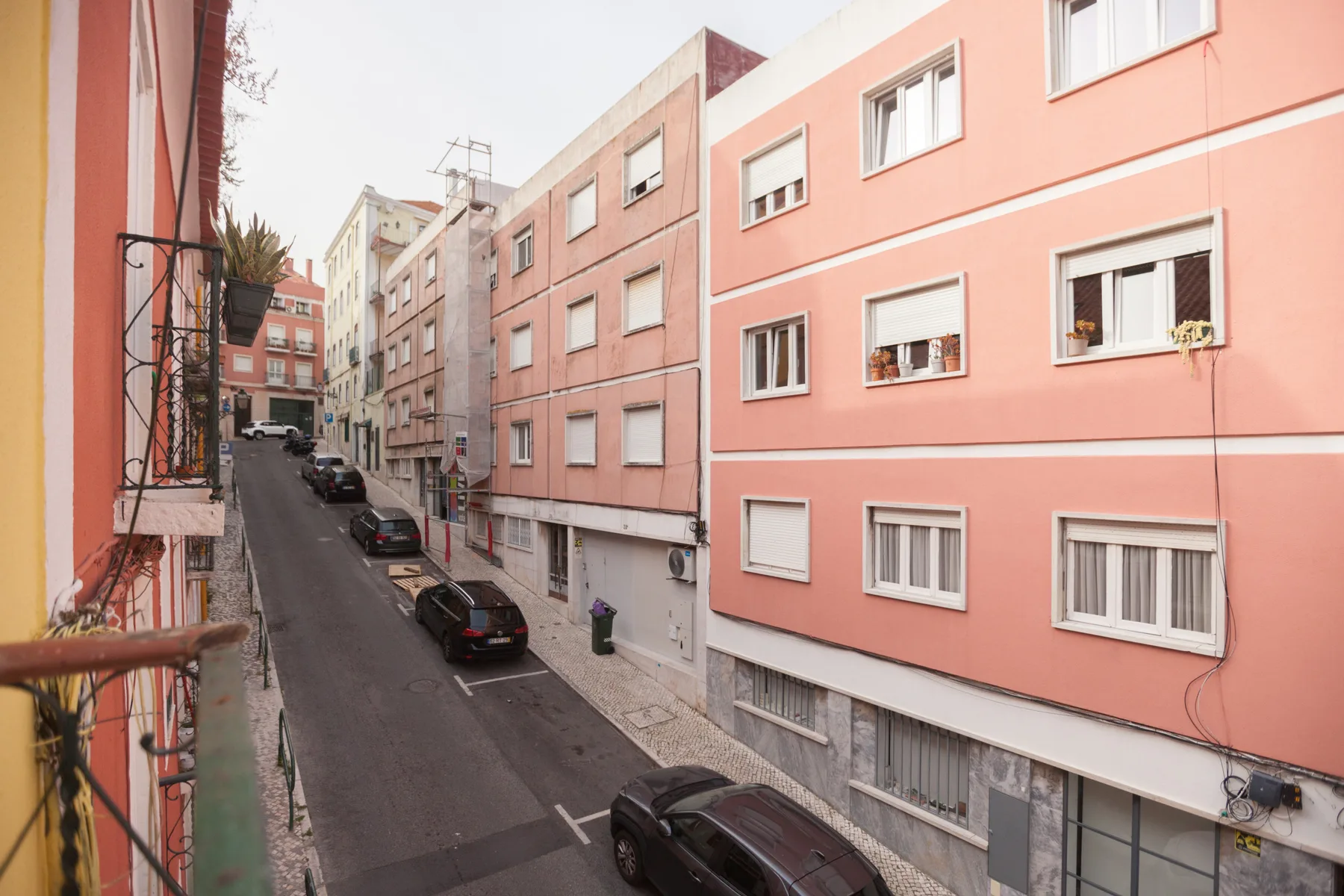 A narrow residential street lined with pastel-colored apartment buildings.