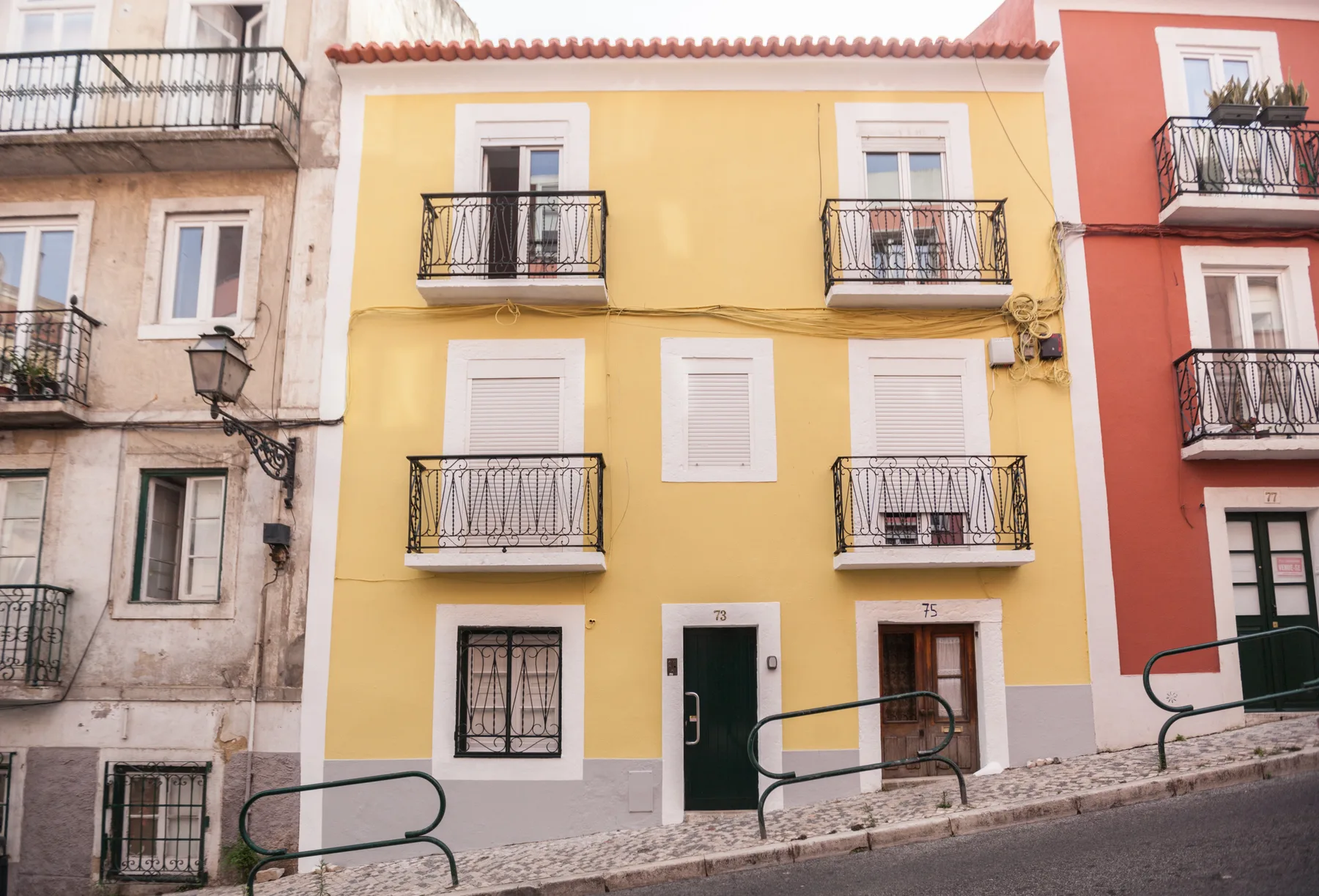 Edificio amarillo con balcones y ventanas enmarcadas en blanco.