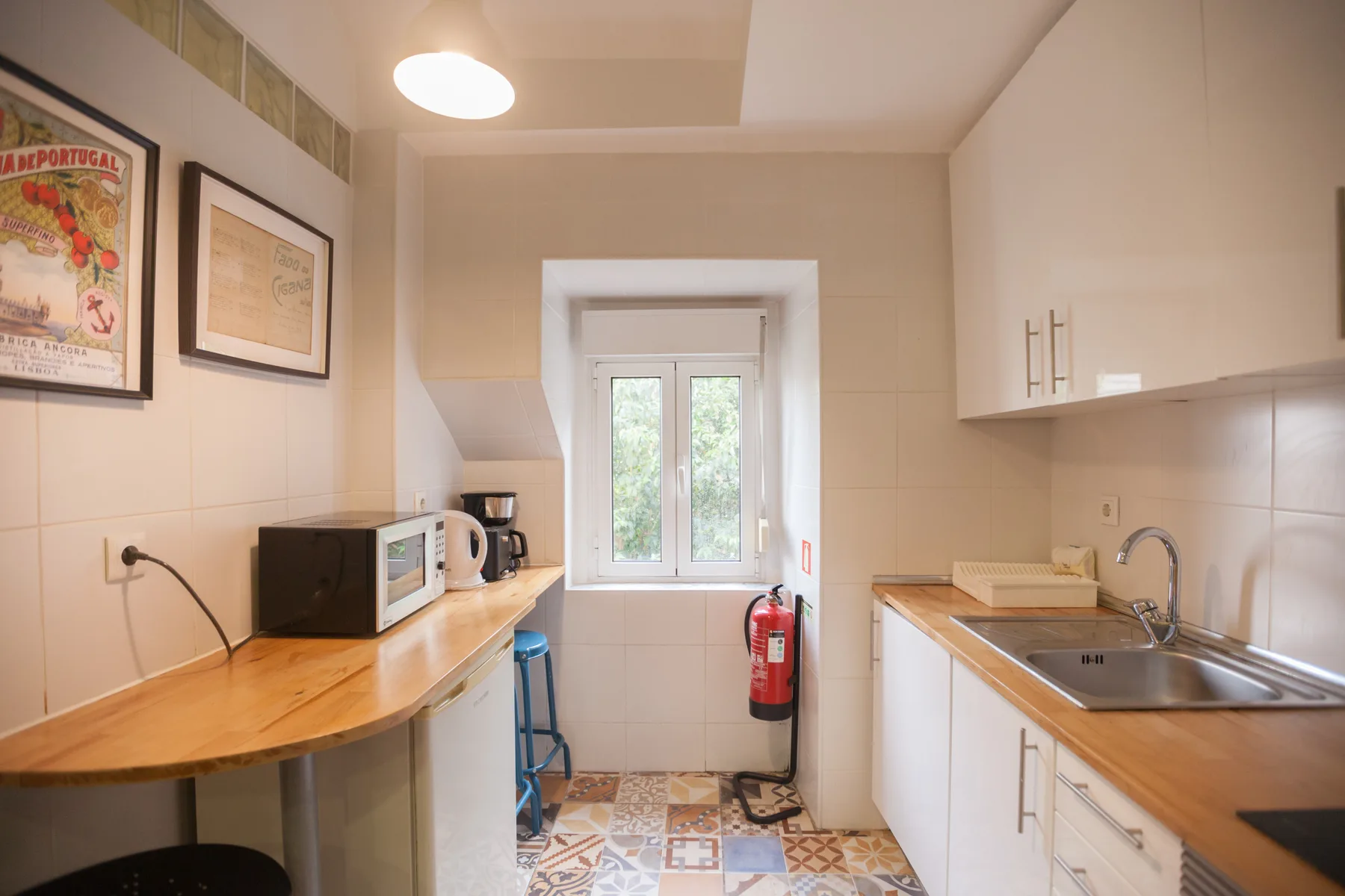 Una cocina compacta tiene encimeras de madera, un fregadero y una ventana al fondo.