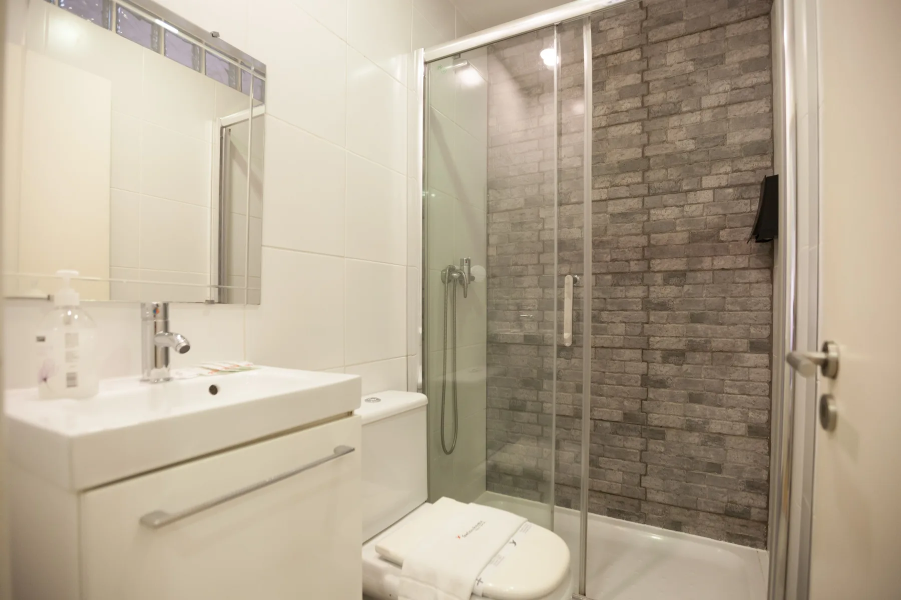 Un baño luminoso con lavabo, inodoro y ducha de vidrio.