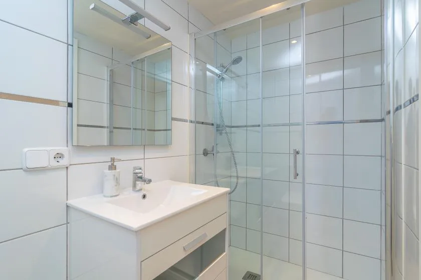 A tiled bathroom with a sink vanity and glass shower.