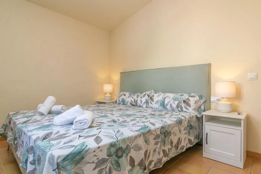 A bedroom with floral bedding and matching bedside tables.