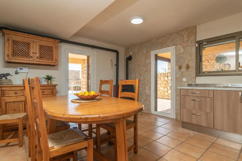 A dining area with a wooden table and chairs beside a stone wall.
