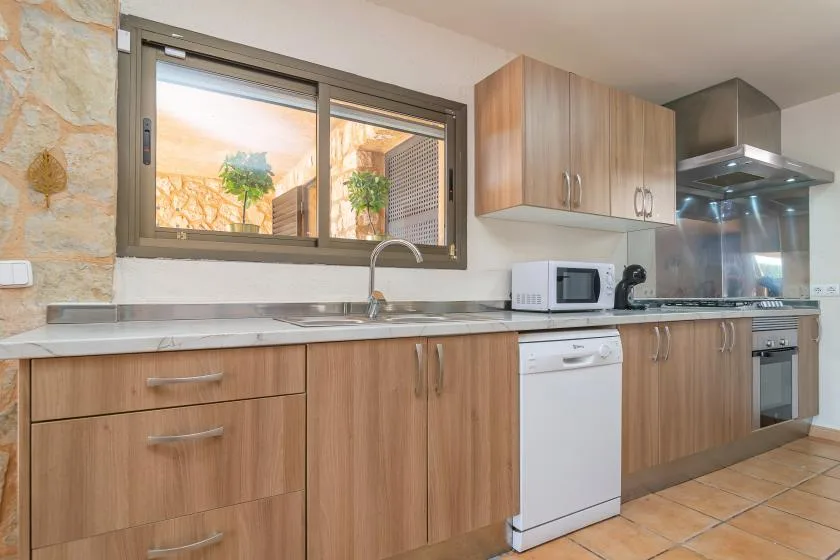 A modern kitchen with wood cabinets, a countertop, and a window above the sink.