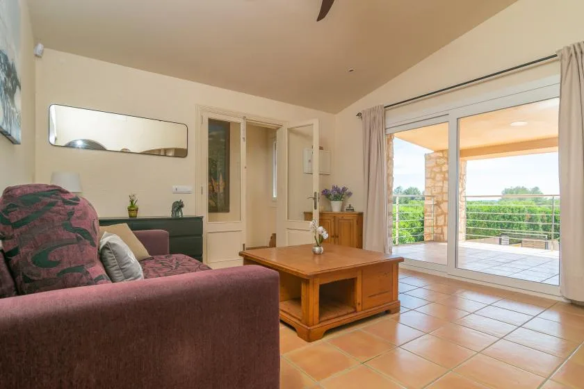 A living room with seating and a coffee table beside glass doors opening onto a terrace.