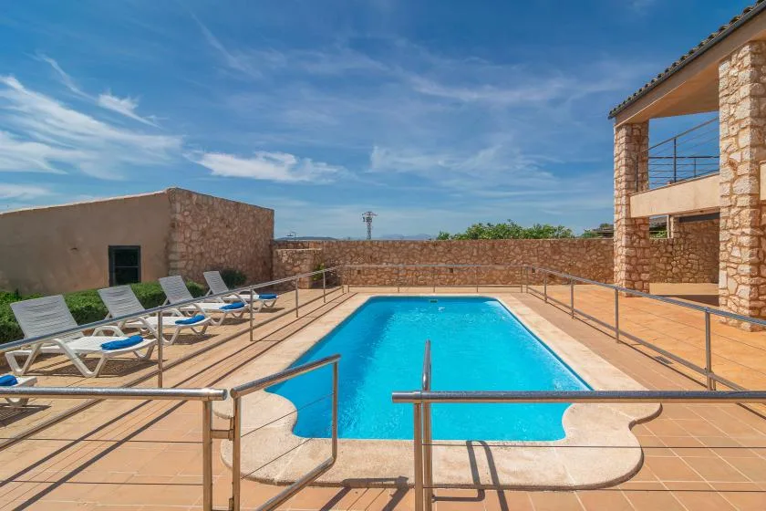 An outdoor swimming pool with lounge seating beside a stone building.