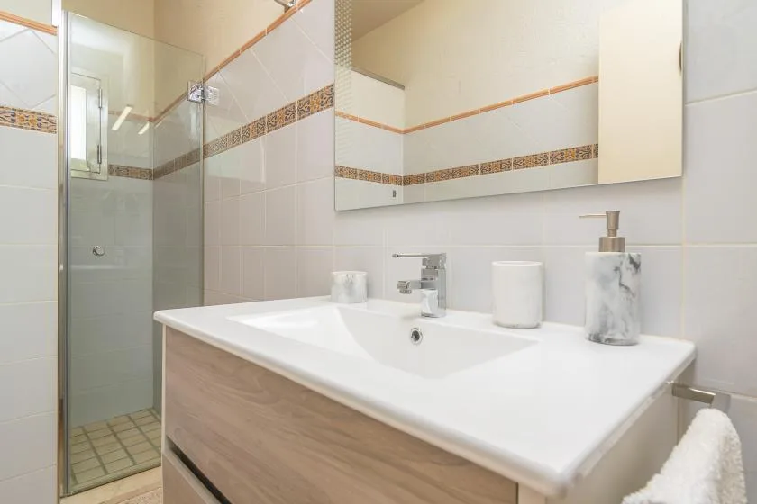 A tiled bathroom with a glass shower and a sink beneath a mirror.