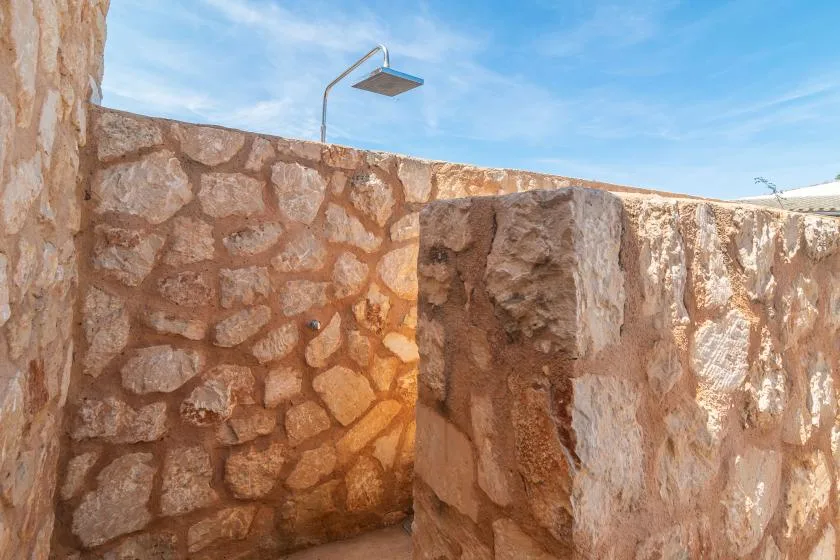 An outdoor shower area with stone walls and an overhead showerhead.