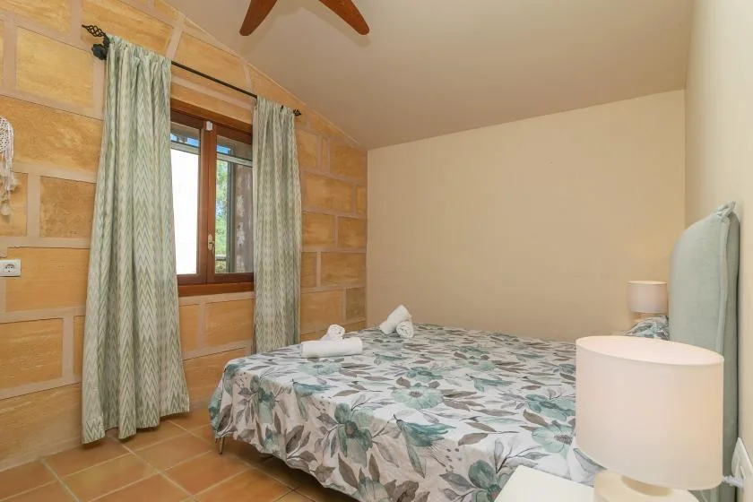 A bedroom with a patterned bedspread and a curtained window.