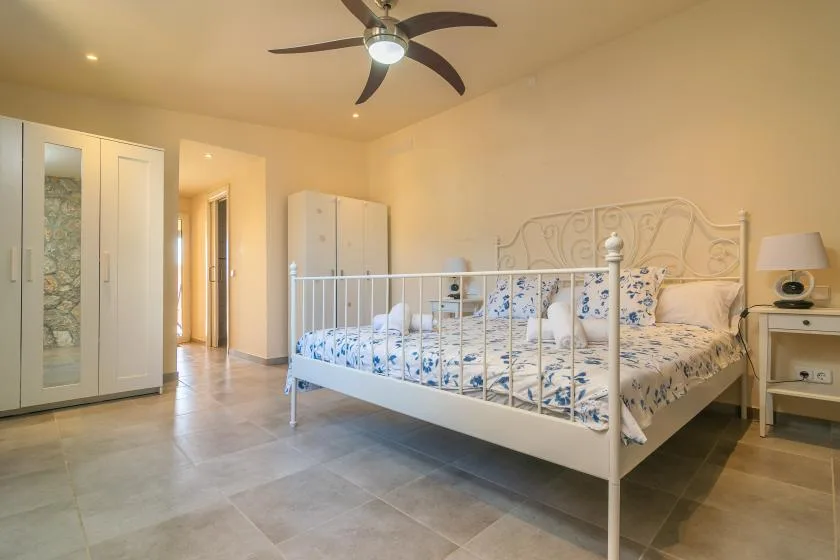 A bedroom with a bed, wardrobe, and ceiling fan.